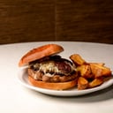 Foto de SANDWICH BONDIOLITA: pan de papa, bondiola braseada, queso, tomate, rúcula y mayonesa de hongos. 