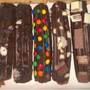 Foto de 6 churros bañados con toppings (oreo,marroc,kinder,rocklets).