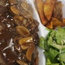 Foto de Churrasco de Ribeye (300gr) en Salsa de Champiñones, papas bravas y ensalada cesar