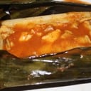 Foto de Tamal de hoja de plátano de salsa roja con pollo.