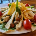 Foto de Pollo grillado, queso gouda, tomates cherries, almendras sobre rúcula (keto)