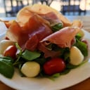 Foto de Jamón crudo, muzzarella, tomates cherries sobre rúcula (keto)