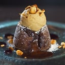 Foto de Soufflé de chocolate con helado de frutos del bosque, geele y salsa de naranja decorada con merenguitos.