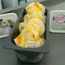 Foto de helado de chirimoya y salsa de naranja, con naranjas confitadas y merenguitos bañados en chocolate y tierra de nuez.