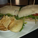 Foto de Sándwich de atún, hojas verdes, lechuga, albahaca, rúcula, tomatitos cherry en pan panini (con papas snack)