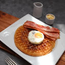 Foto de waffles con huevo frito, tocineta o salchichitas