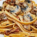 Foto de Fetuccine con salsa de vino tinto, ajo confitado, pesto tomates asados y maní crocante