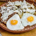 Foto de Chilaquiles con pollo o milanesa, 2 huevos revueltos o estrellados acompañados con frijoles 