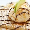 Foto de Panqueques con dulce de leche y una bocha de helado. 