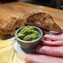 Foto de Desayuno Clásico: cafe / te, tostadas, porción de jamón y queso, guacamole, jugo natural de naranjas y frutas frescas