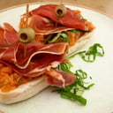 Foto de Brocheta en pan tumaca con jamón serrano y aceituna