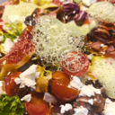 Foto de Ensalada de higos con nueces cubiertas de chocolate, cherry, queso feta, miel de pera, beicon crujiente y aire de albahaca