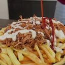 Foto de Papas fritas, carne mechada, cebolla caramelizada y un huevo