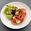 Foto de Tosta mediterránea, con tapenade de olivas negras, jamón crudo, bocconcinis, tomates asados y aceite de albahaca.