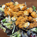 Foto de Pizzolo César con pollo crujiente, emulsión de anchoas, cherrys, mezclum, mozzarella, parmesano y kikos