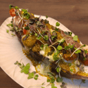 Foto de Tosta de anchoa de Santoña con hogaza de calabaza casera, cherrys asados en miel, queso mozzarella, pesto rojo y aceituna